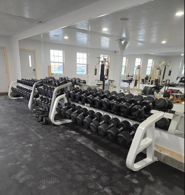 Iron Edge Fitness training floor with extensive free weight collection, benches, and plate-loaded machines